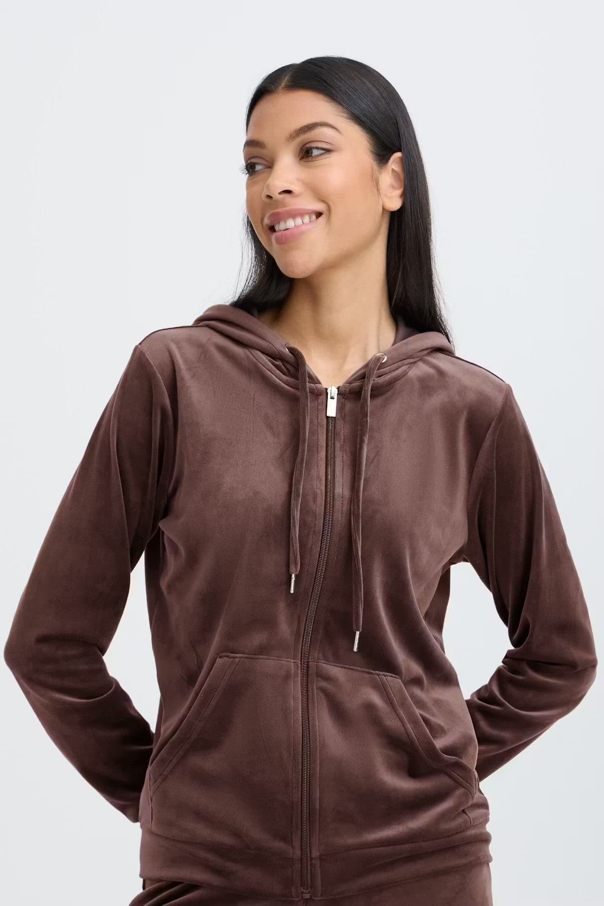 Model in a brown velour zip-up hoodie, studio background
