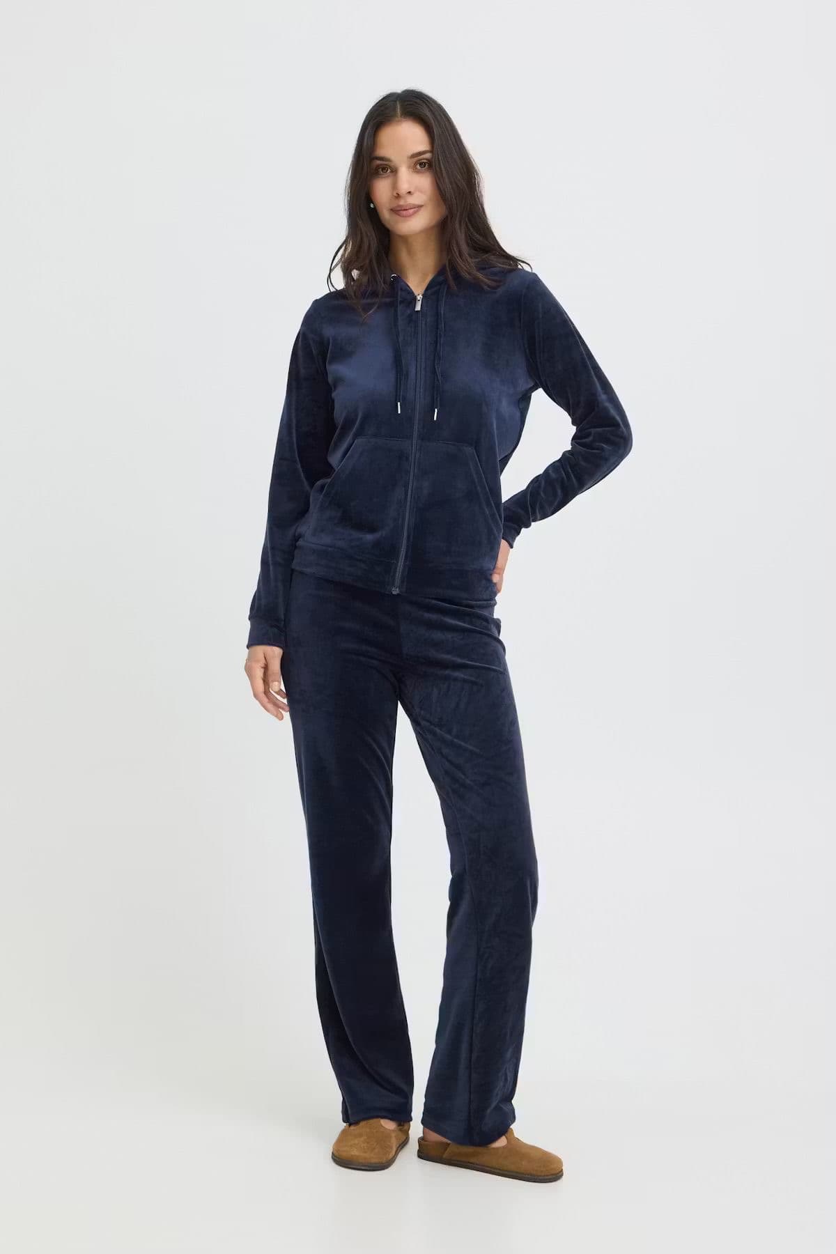 Model in a matching navy velour zip-up and wide trousers set, studio background