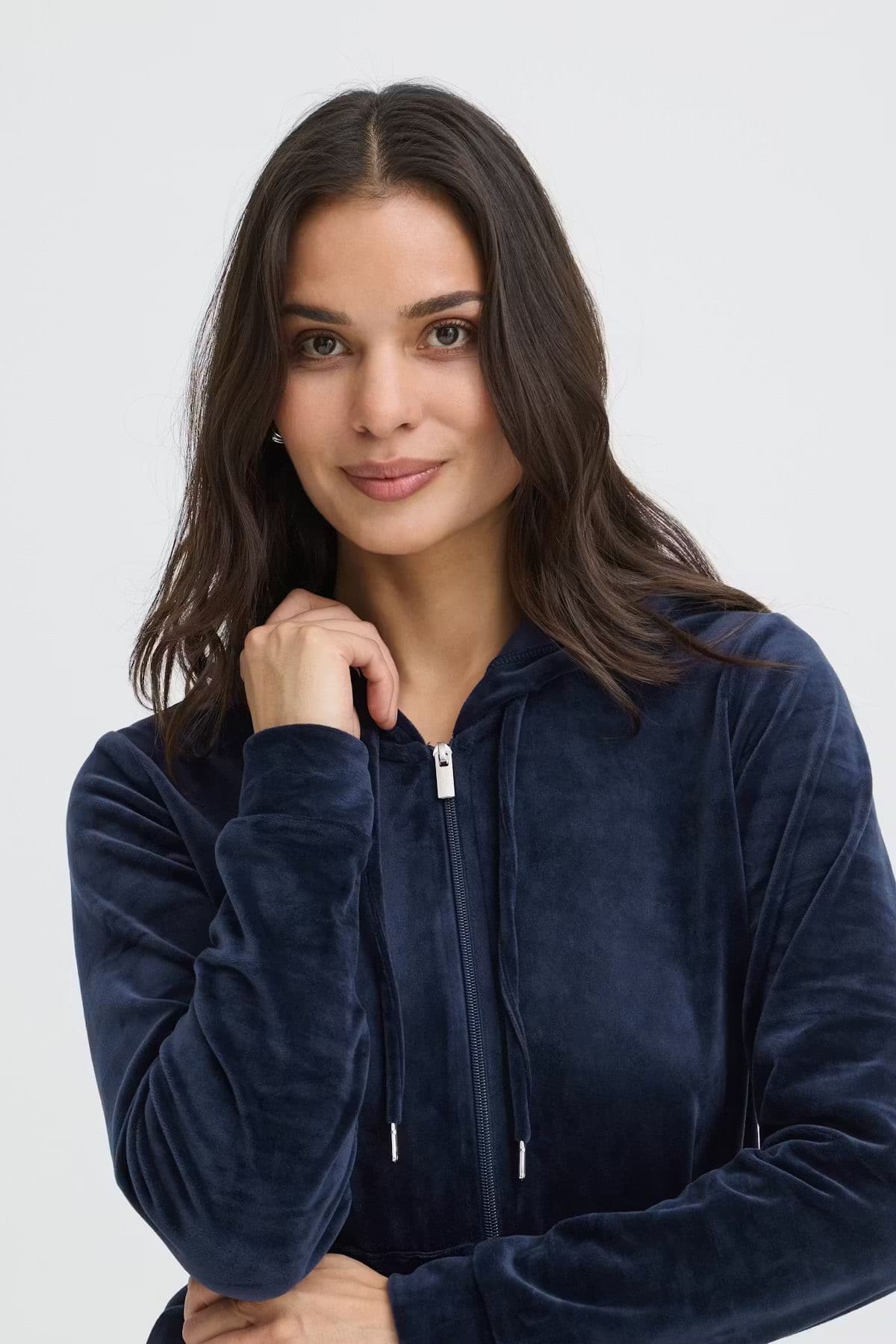 Model in a navy velour top standing between street pillars