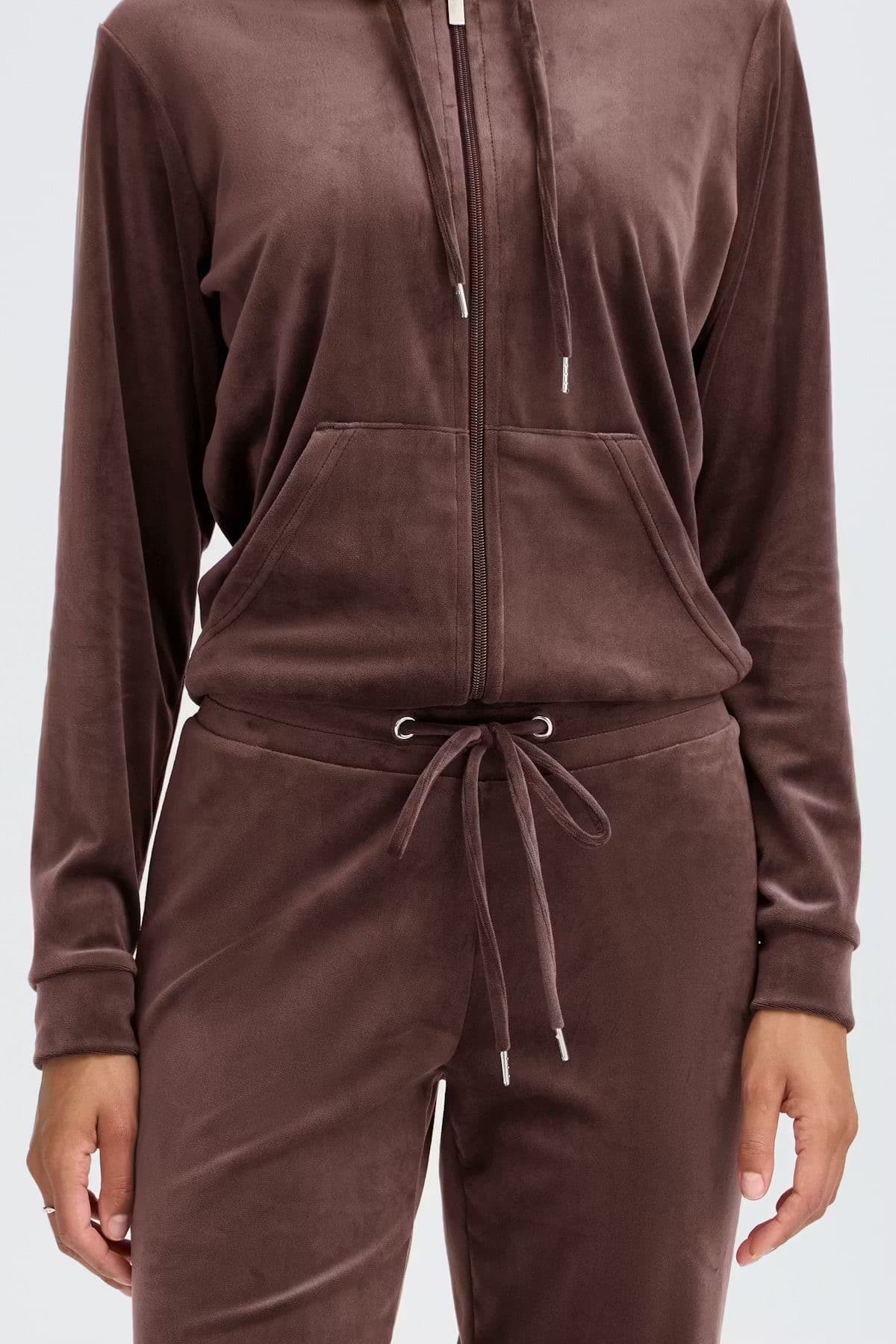 Model in a brown velour matching zip-up and trousers set, studio background