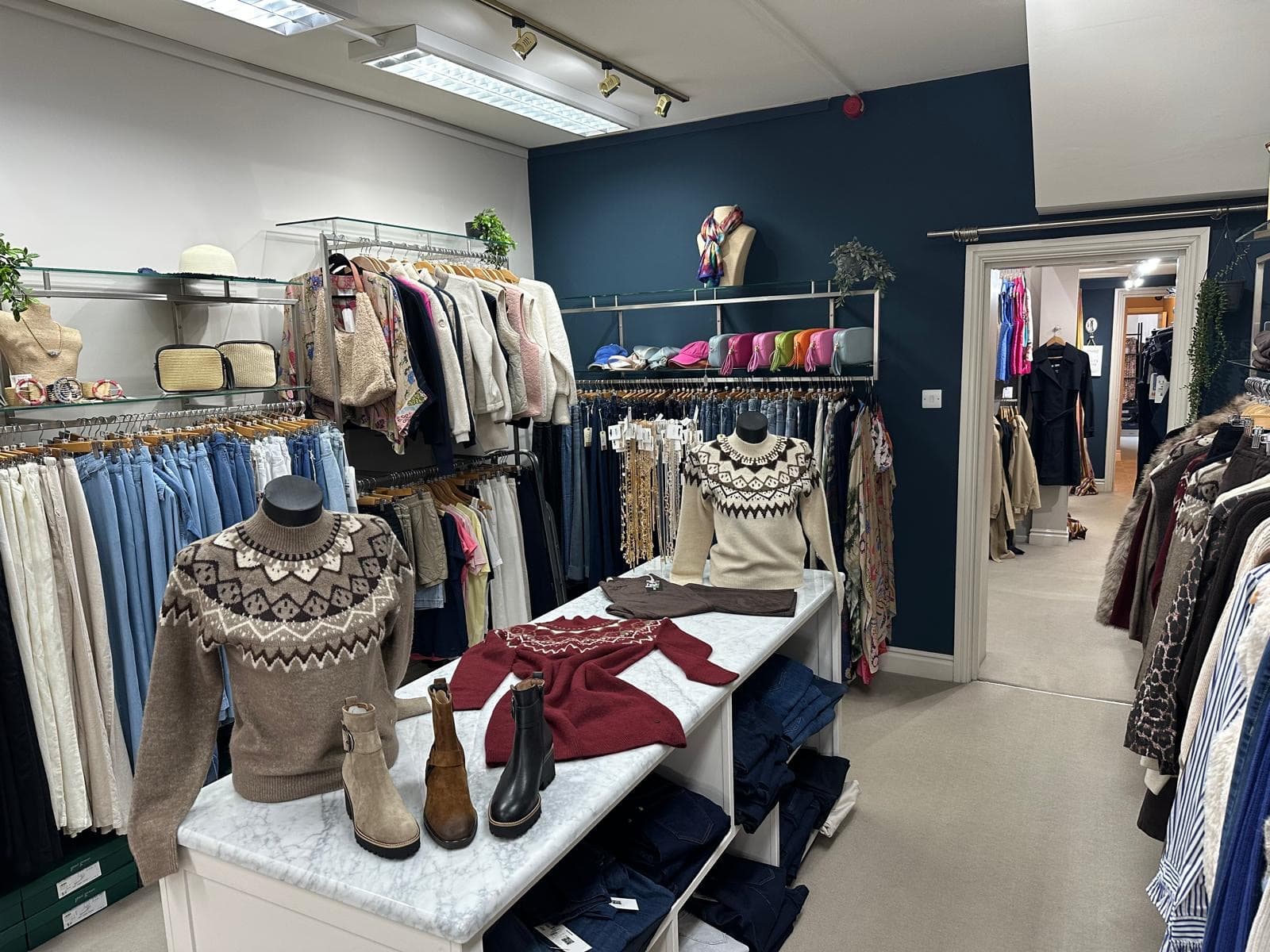 Knitwear and accessories displayed against the boutique's navy-painted wall